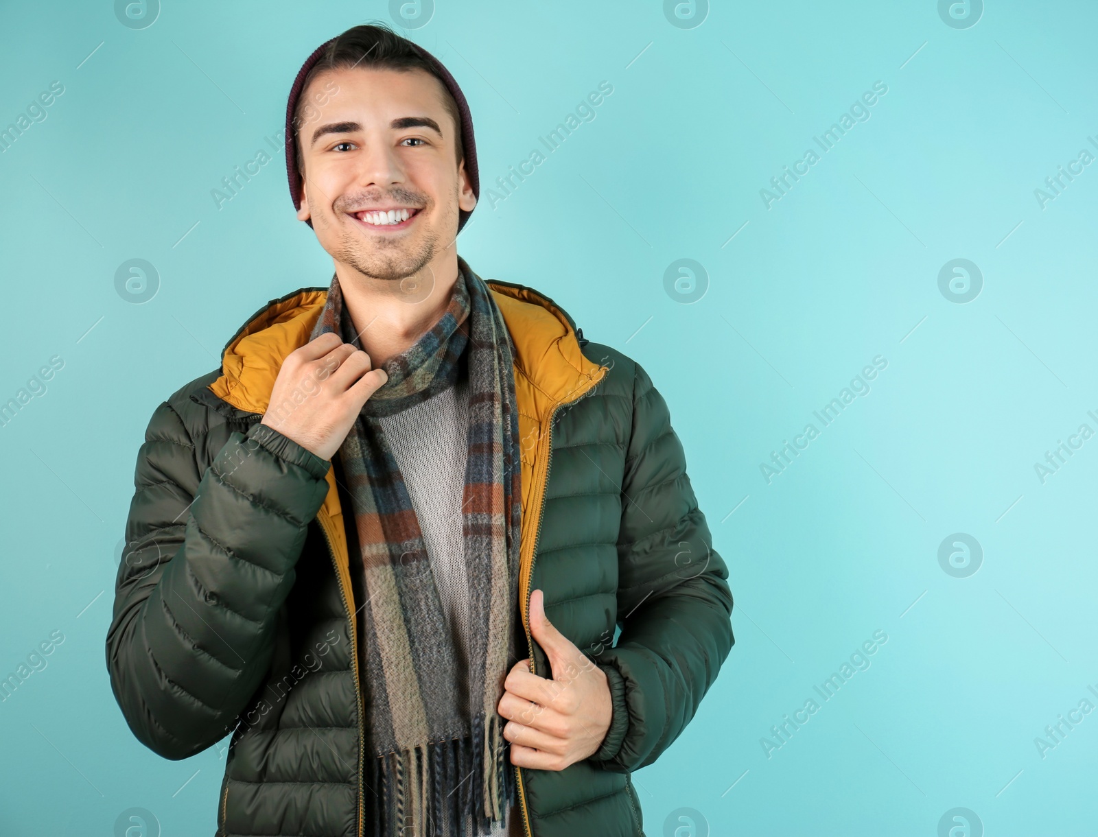 Photo of Portrait of happy young man in warm clothing on color background. Ready for winter vacation