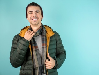 Portrait of happy young man in warm clothing on color background. Ready for winter vacation