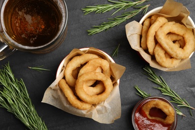 Photo of Fried onion rings served on black table, flat lay