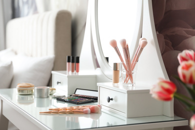 Set of makeup products and cosmetic brushes on dressing table indoors. Interior design