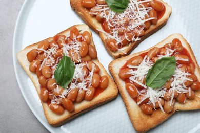Photo of Toasts with delicious canned beans on light grey table, top view