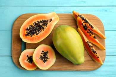 Photo of Fresh ripe papaya fruits on turquoise wooden table, flat lay