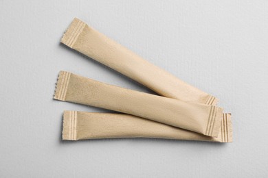 Beige sticks of sugar on light grey background, flat lay