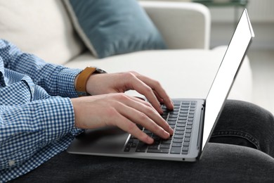 Photo of Man working with laptop on sofa indoors, closeup