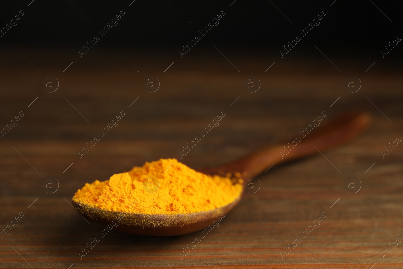 Photo of Spoon with saffron powder on wooden table