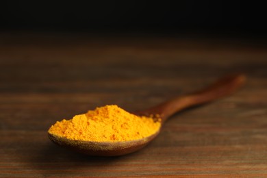 Photo of Spoon with saffron powder on wooden table