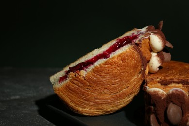 Photo of Tasty puff pastry. Round croissant with jam, cream and chocolate chips on grey table, closeup. Space for text