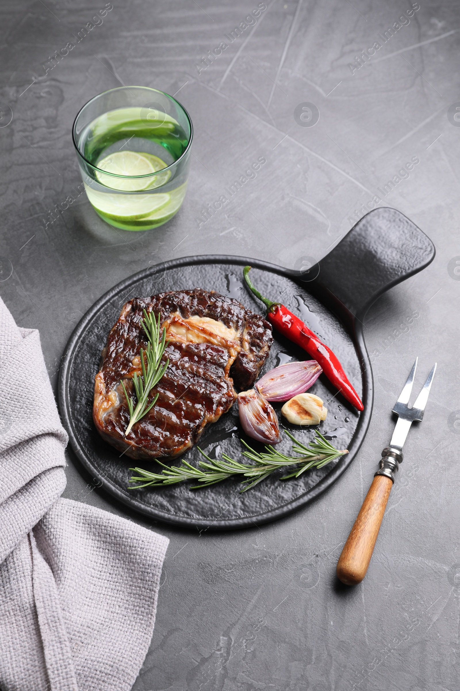 Photo of Delicious grilled beef meat served on gray textured table, above view