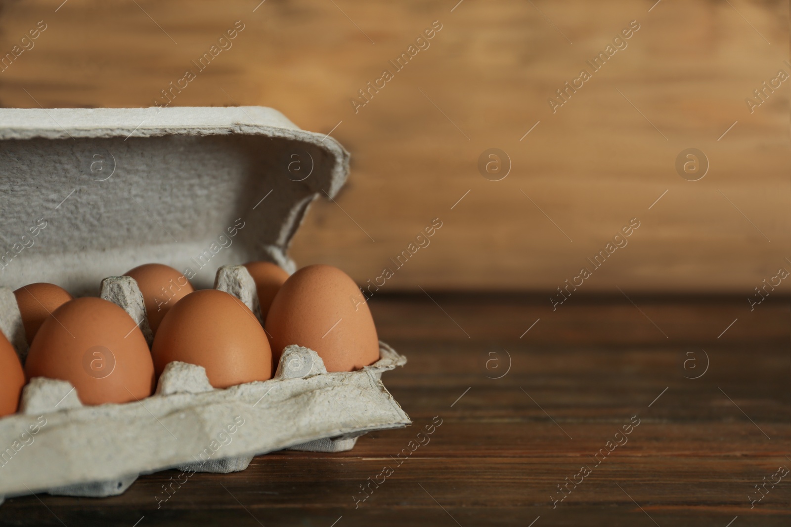 Photo of Raw chicken eggs on wooden table. Space for text