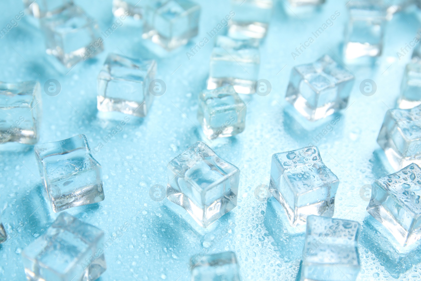 Photo of Ice cubes and water drops on turquoise background. Ingredient for refreshing drink