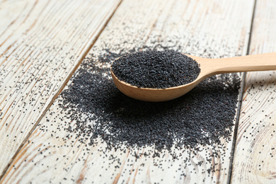 Photo of Poppy seeds in spoon on white wooden table