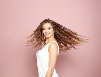 Portrait of beautiful young woman with shiny wavy hair on color background