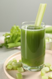 Photo of Glass of delicious celery juice and vegetables on grey table, closeup