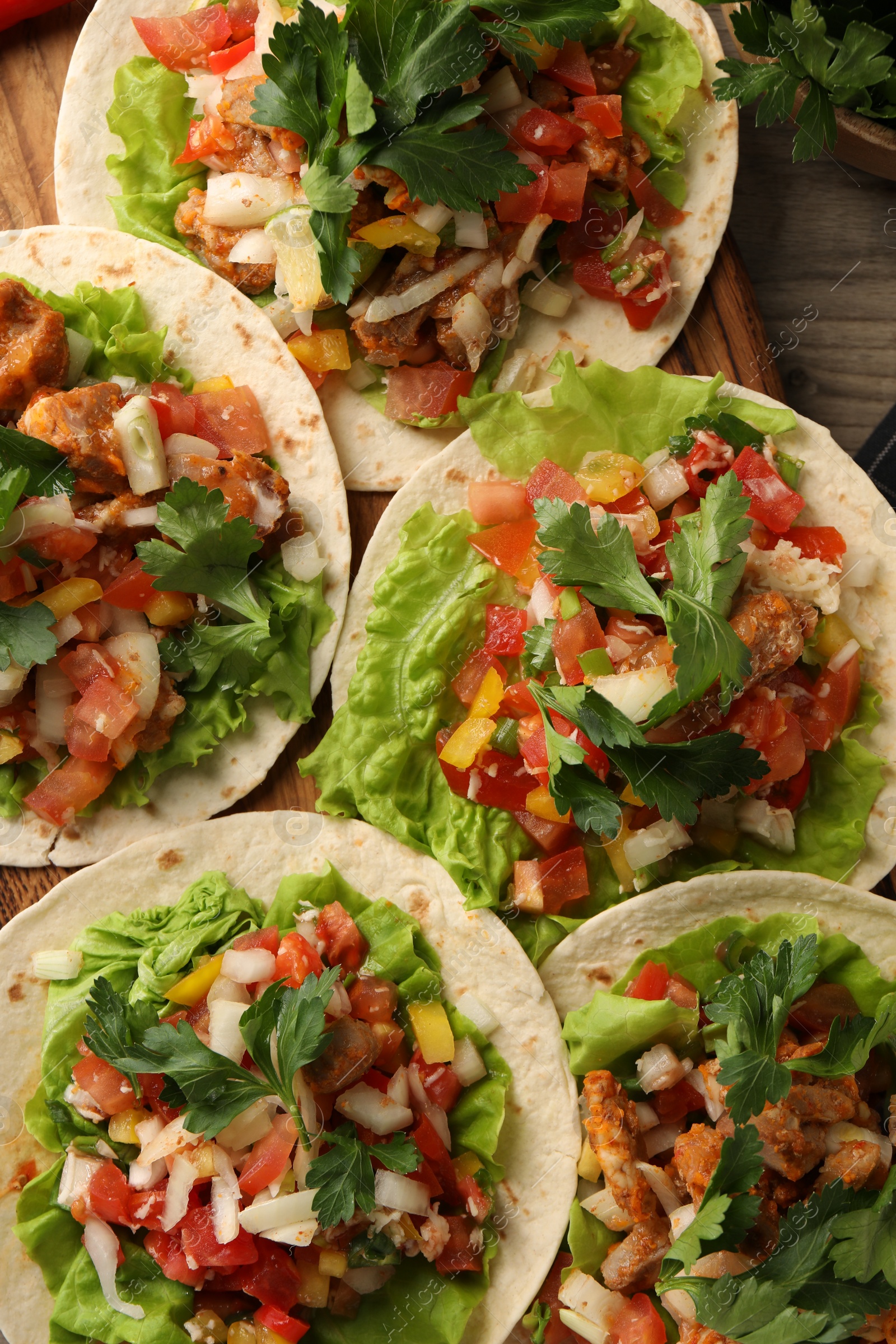 Photo of Delicious tacos with vegetables and meat on table, flat lay