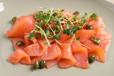 Photo of Delicious salmon carpaccio with capers and microgreens on plate, closeup