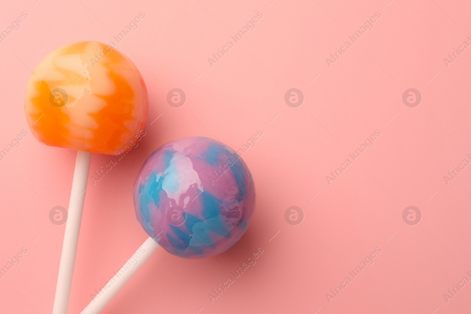 Photo of Tasty lollipops on pink background, flat lay. Space for text