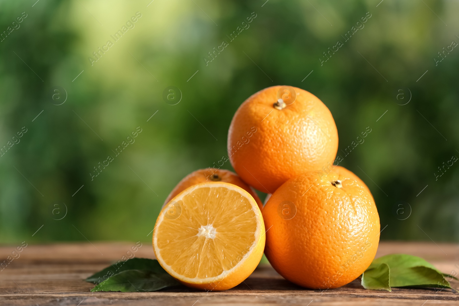 Photo of Fresh ripe oranges on wooden table against blurred background. Space for text