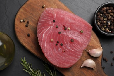 Photo of Raw tuna fillet and spices on black table, flat lay