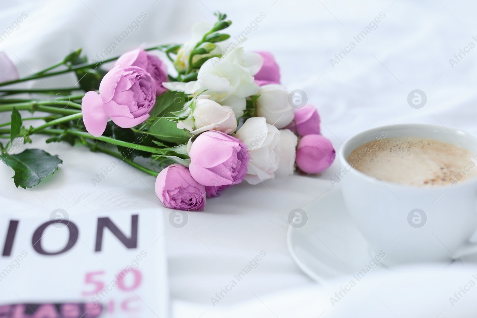 Photo of Cup of coffee, beautiful flowers and magazine on fabric