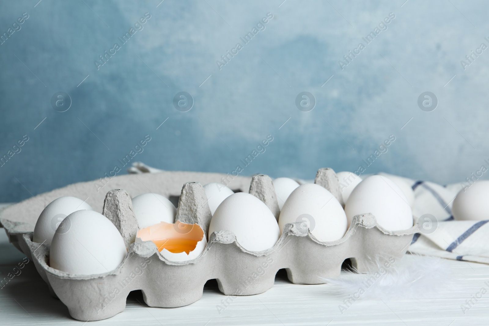 Photo of Fresh raw chicken eggs in box on white table. Space for text