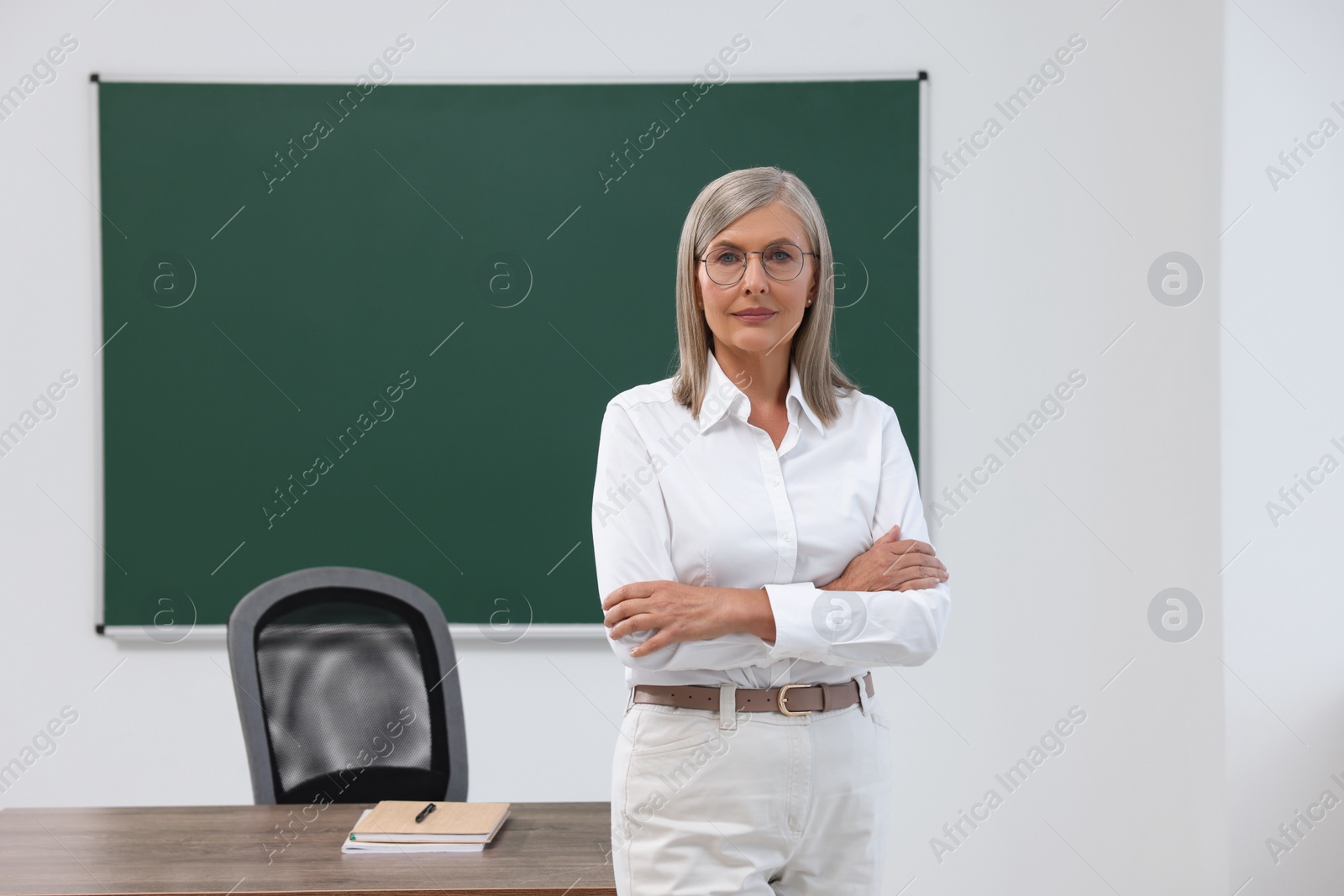 Photo of Portrait of professor near blackboard in classroom, space for text