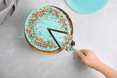 Woman taking slice of fresh delicious birthday cake at table, top view