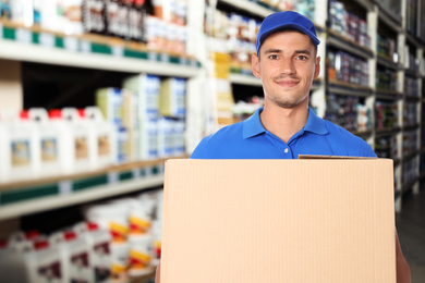 Image of Man wearing uniform with cardboard box in store. Wholesale market