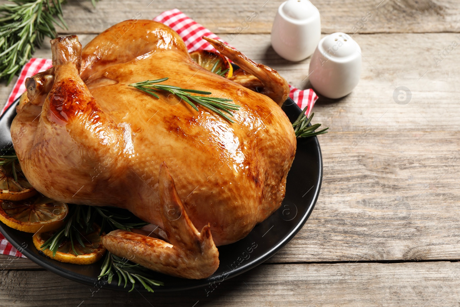 Photo of Tasty roasted chicken with rosemary and lemon on wooden table