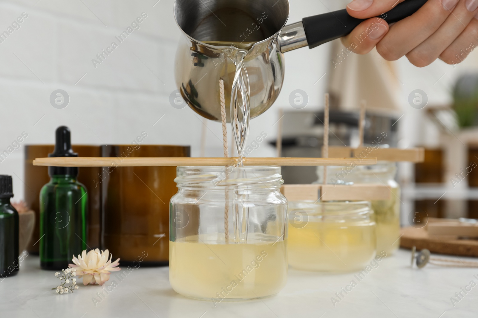 Photo of Woman making candles at white table, closeup