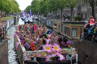 Photo of AMSTERDAM, NETHERLANDS - AUGUST 06, 2022: Many people in boats at LGBT pride parade on river