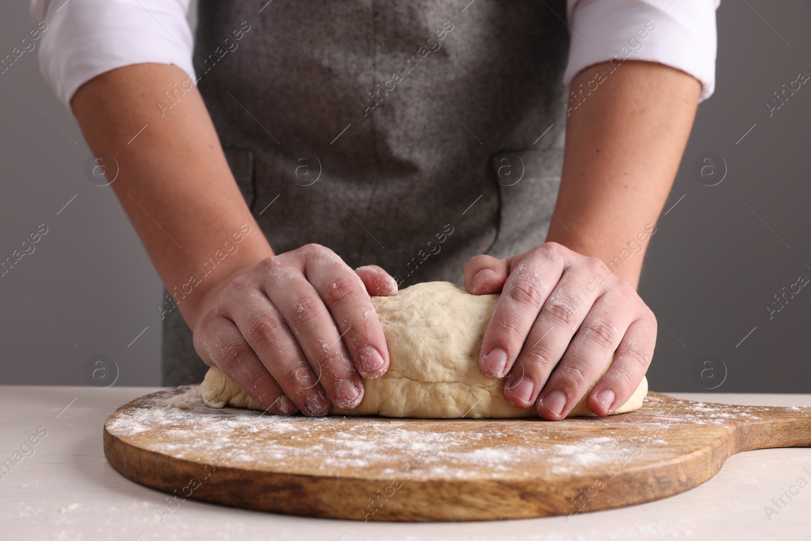 Photo of Man kneading dough at table near grey wall, closeup