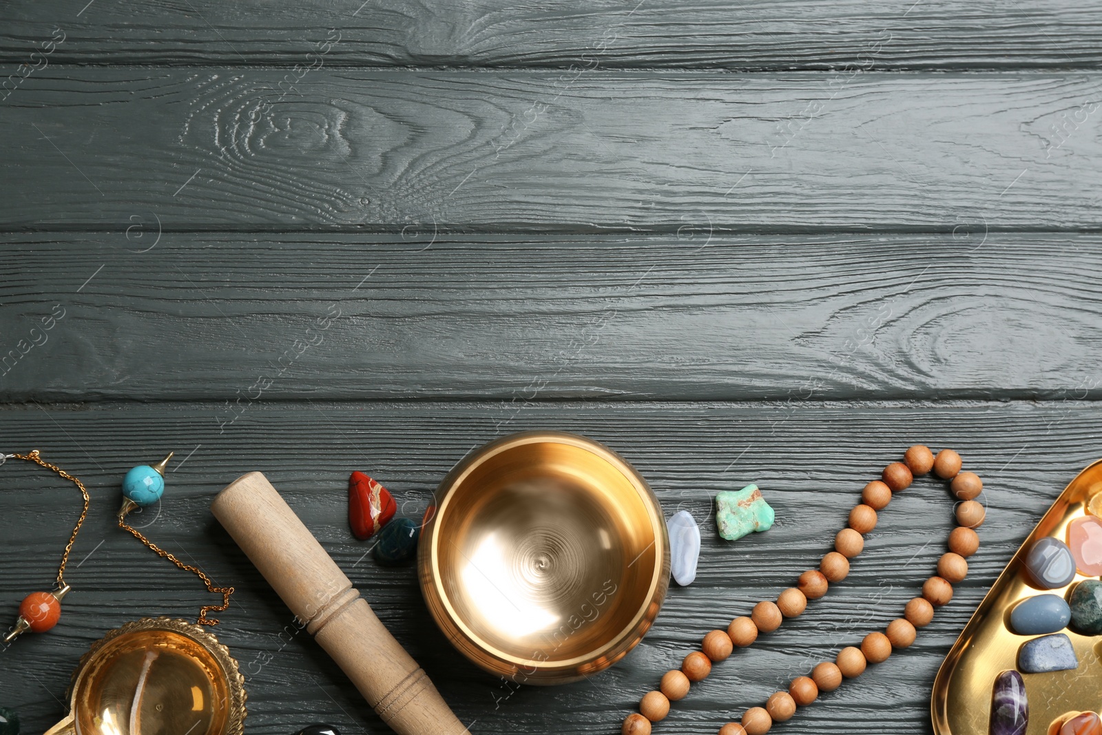 Photo of Flat lay composition with golden singing bowl on grey wooden table, space for text. Sound healing