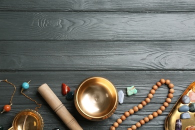 Flat lay composition with golden singing bowl on grey wooden table, space for text. Sound healing