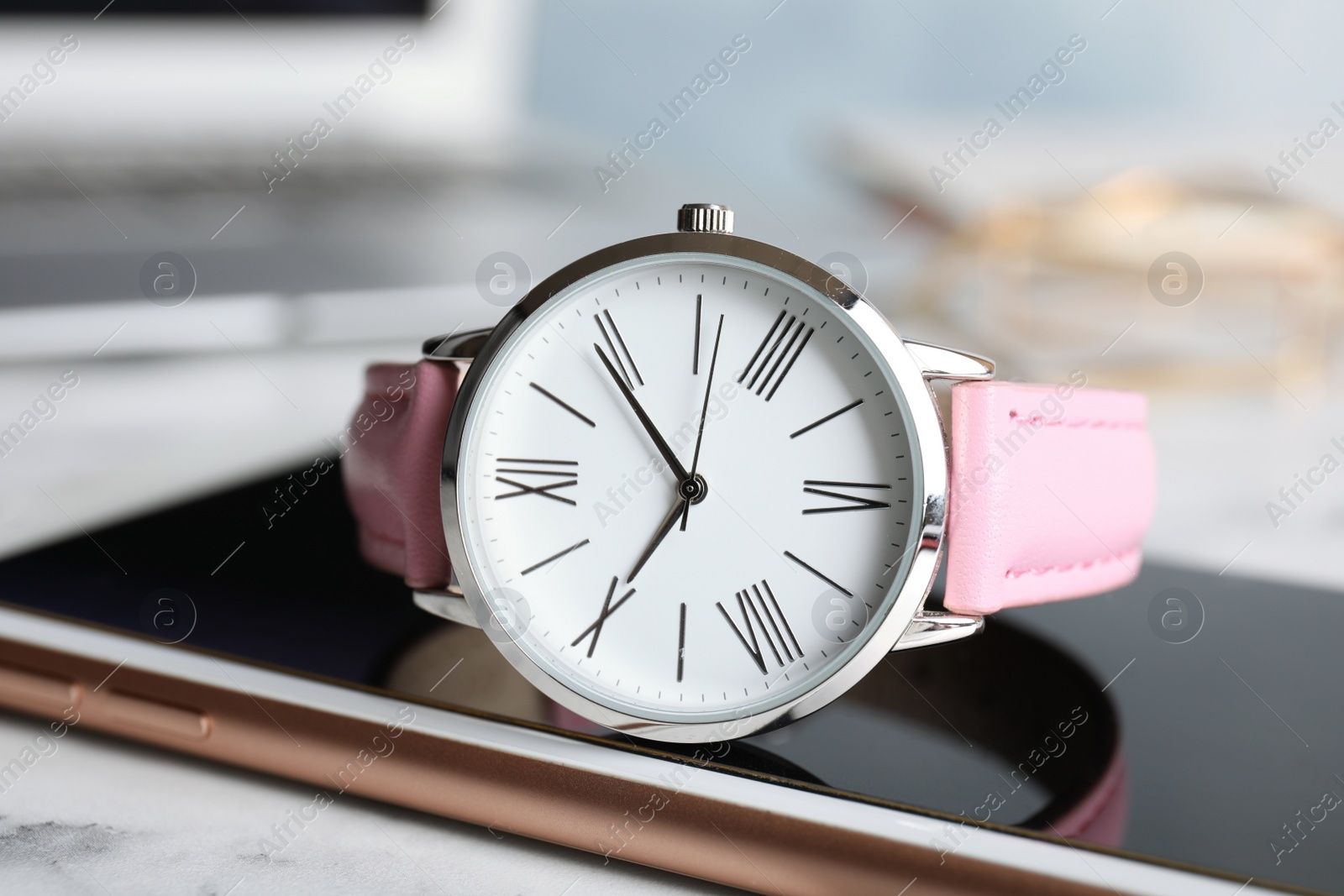 Photo of Stylish wrist watch with modern smartphone on marble table. Fashion accessory