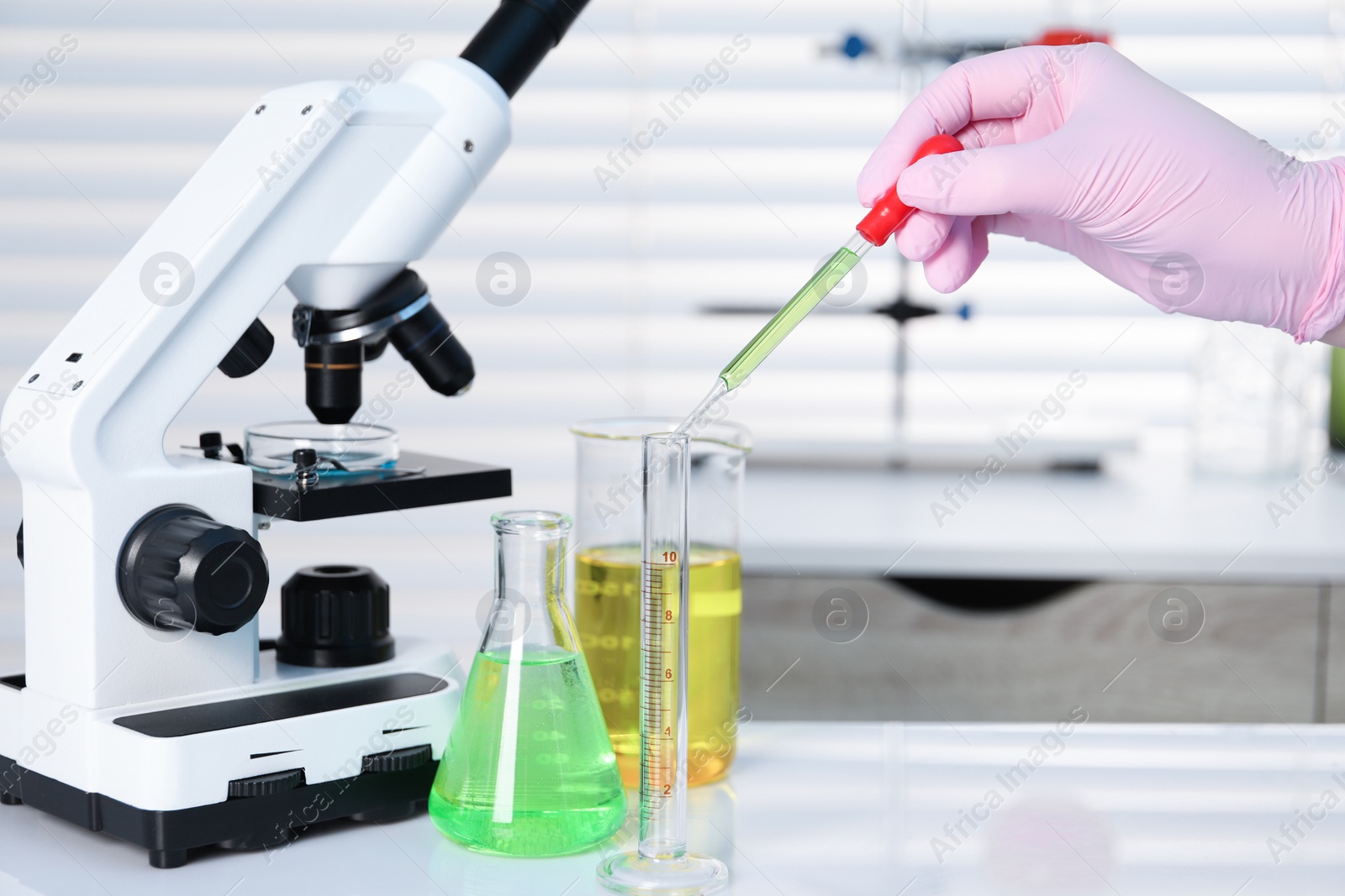 Photo of Laboratory analysis. Woman dripping liquid into test tube on white table indoors, closeup