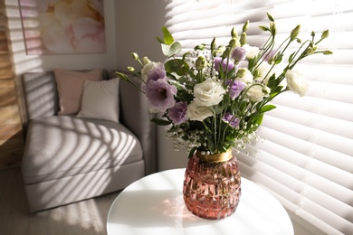 Photo of Bouquet of beautiful Eustoma flowers on table in room. Space for text