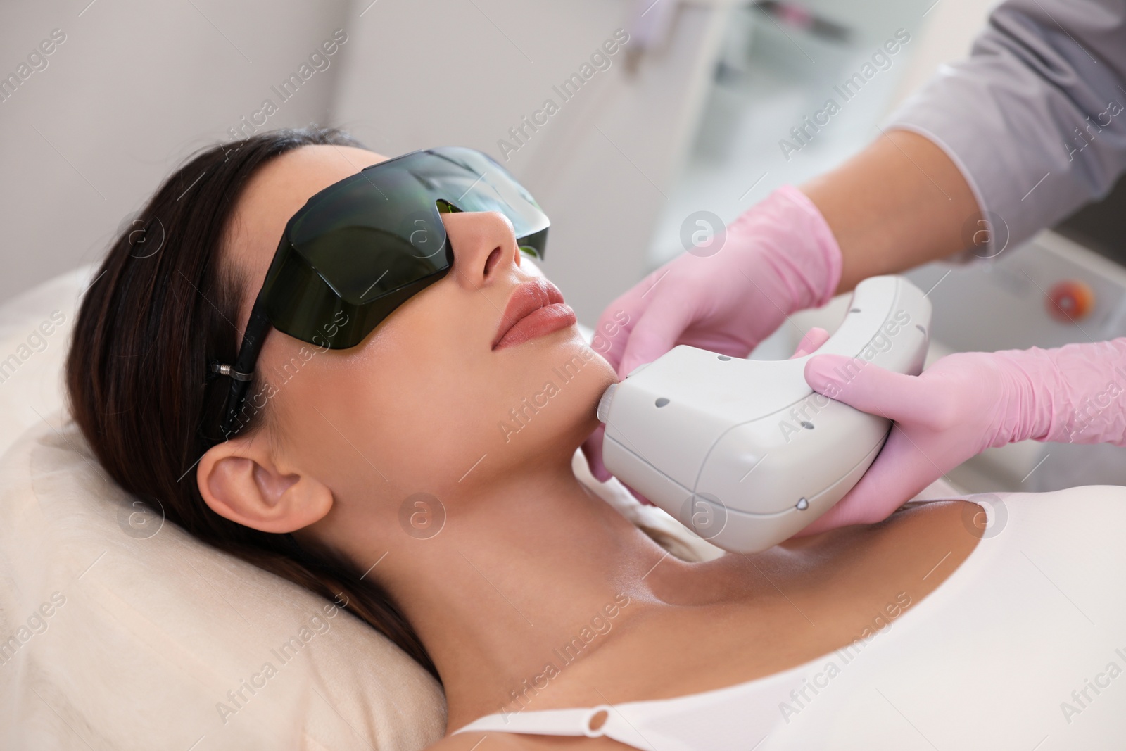 Photo of Young woman undergoing laser epilation procedure in beauty salon