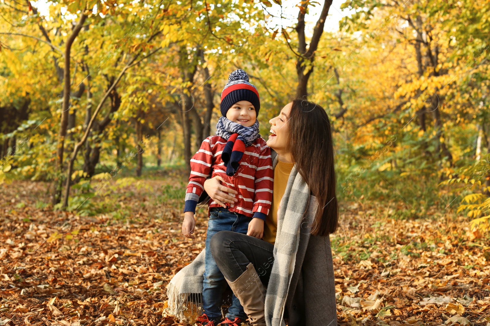 Photo of Mother with her cute son spending time together in park. Autumn walk