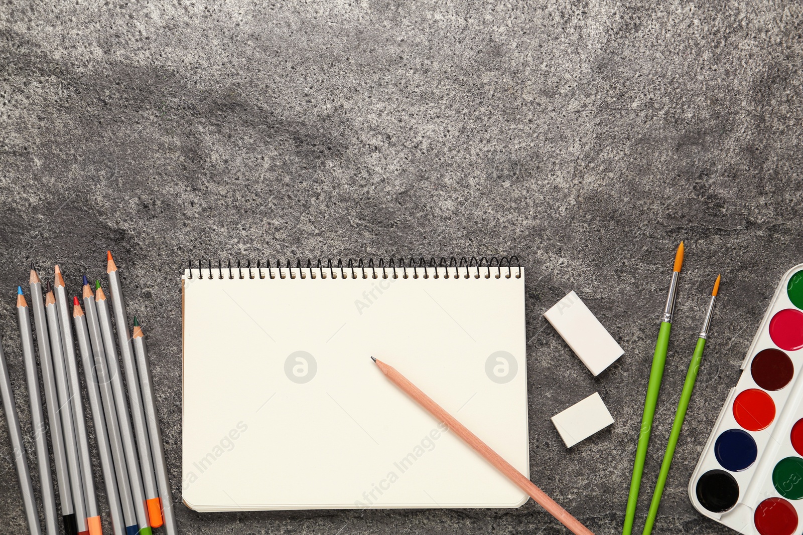 Photo of Flat lay composition with blank sketchbook on grey stone table. Space for text