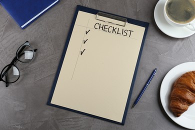 Photo of Clipboard with inscription Checklist, eyeglasses, cup of coffee and croissant on grey table, flat lay