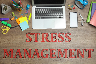 Laptop, stationery and text STRESS MANAGEMENT on wooden table, flat lay