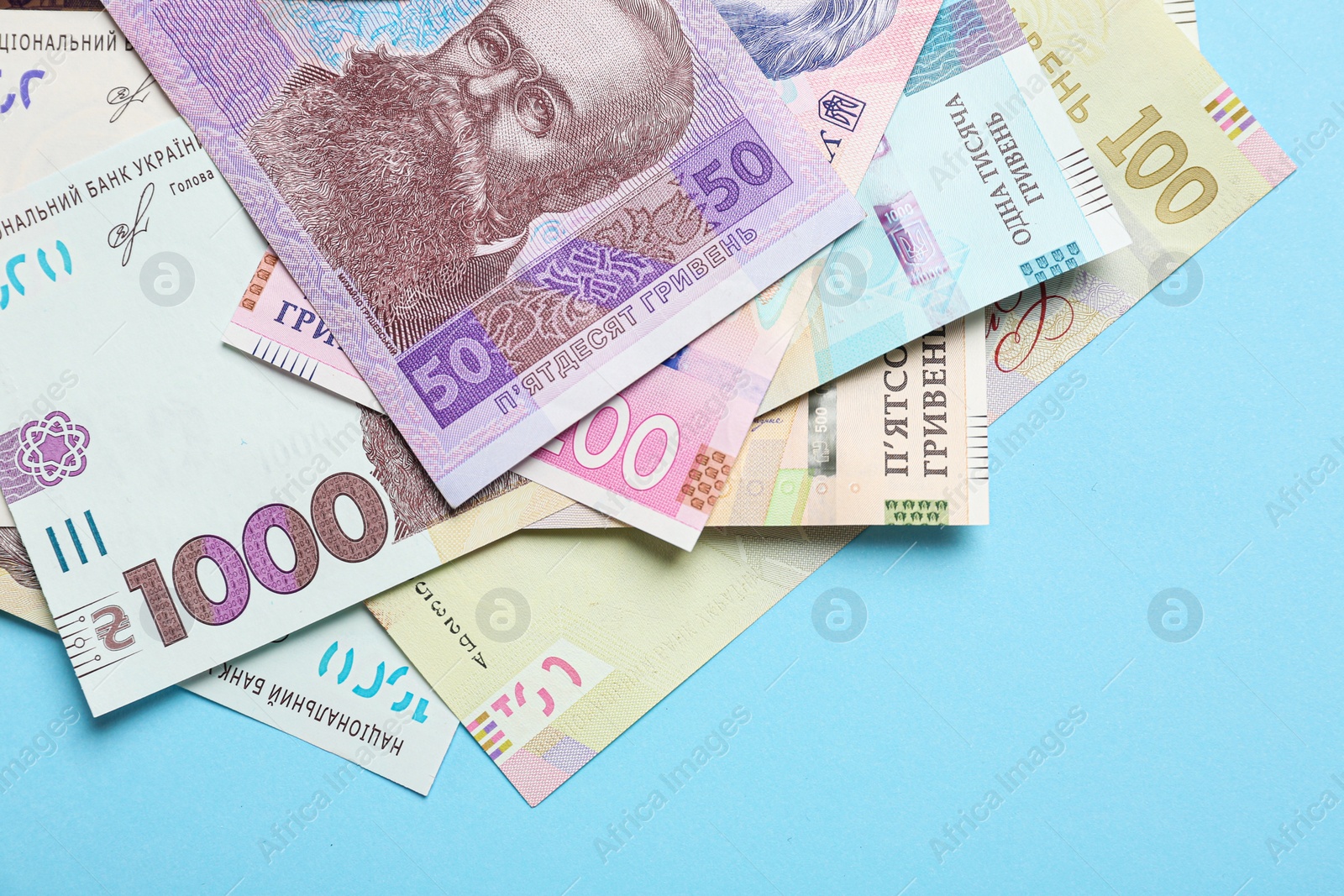 Photo of Ukrainian money on light blue background, flat lay