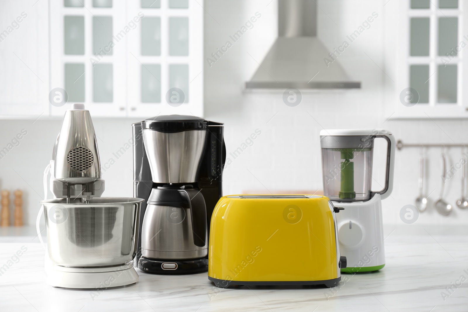 Photo of Modern toaster and other home appliances on white marble table in kitchen