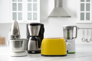 Modern toaster and other home appliances on white marble table in kitchen