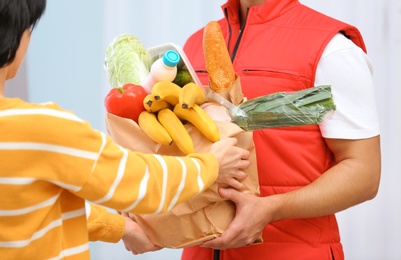 Photo of Male courier delivering food to client on light background, closeup