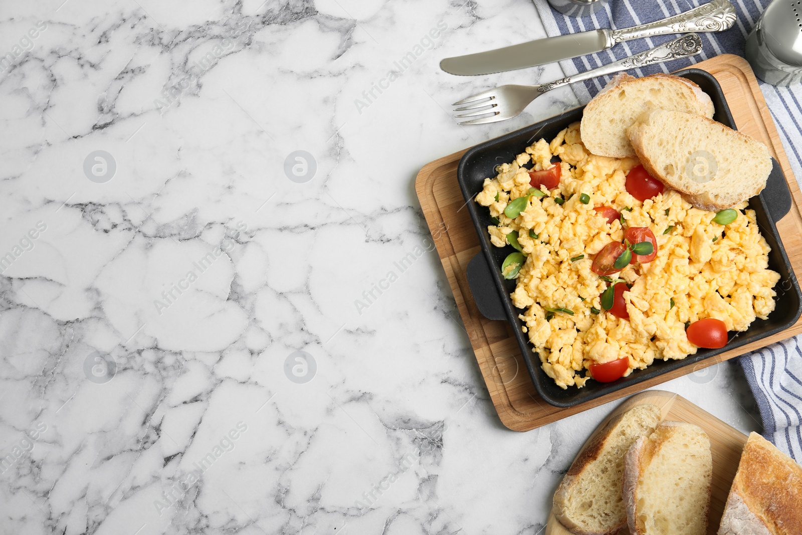 Photo of Tasty scrambled eggs served on white marble table, flat lay. Space for text