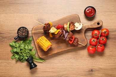 Photo of Delicious shish kebabs served on wooden table, flat lay
