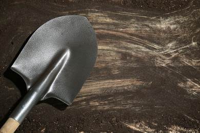 Photo of Metal shovel on dirty wooden surface, top view. Space for text