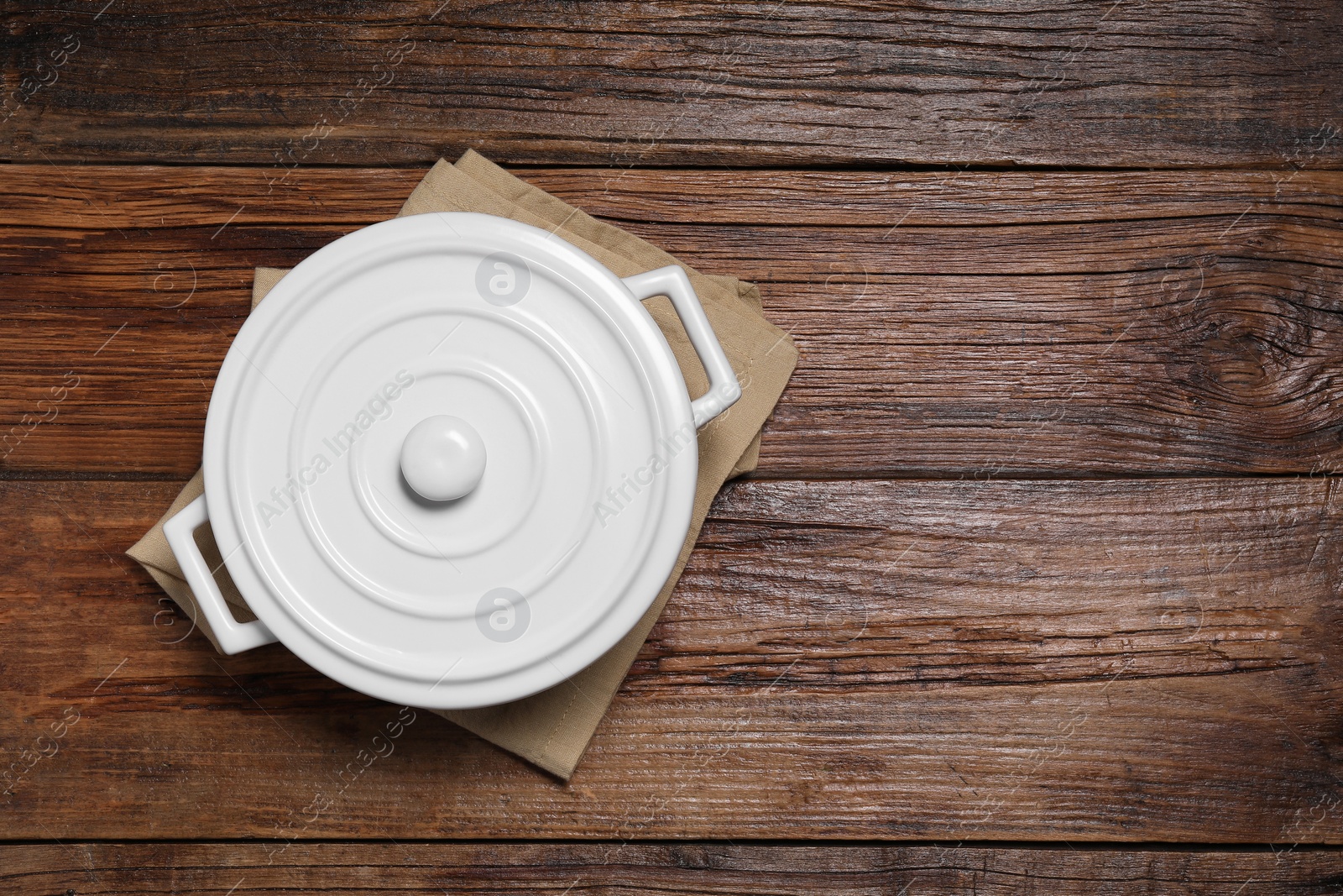 Photo of White ceramic pot with lid on wooden table, top view. Space for text