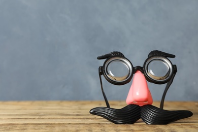 Photo of Funny face made with clown's accessories on wooden table against grey background, space for text